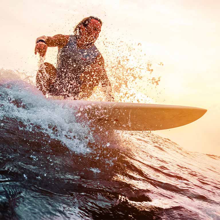 Surfer rides ocean sunset