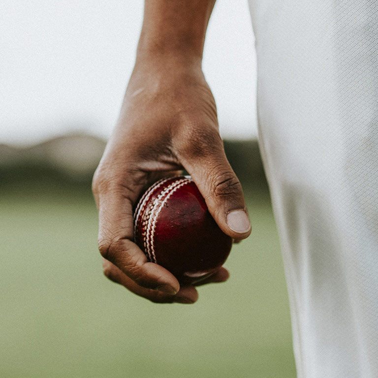 Cricket player holding a leather ball.